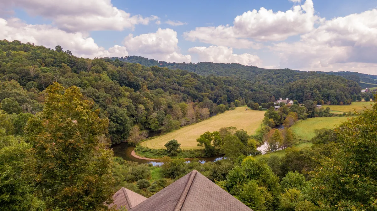 This image offers a sweeping view of rolling hills, a meandering river, lush trees, and an open field. The landscape is serene and expansive, encapsulating the peaceful and inspiring natural environment referenced in the section.