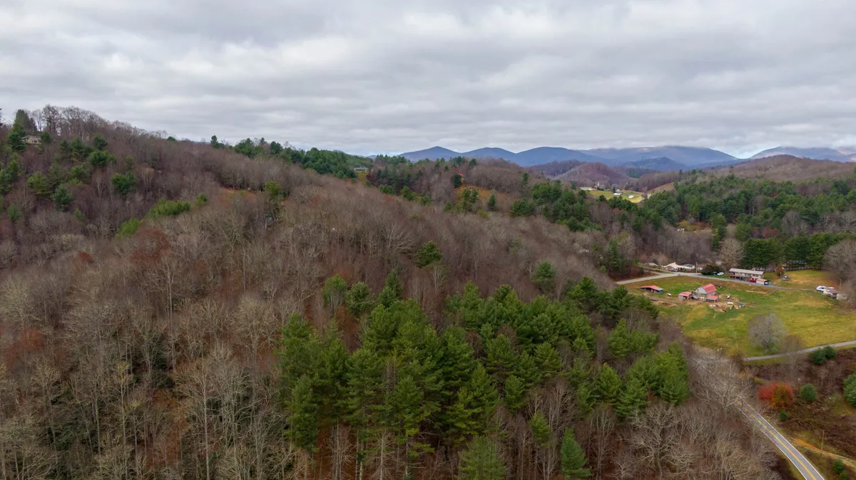 An expansive view of rolling hills, dense forests, and scattered farms, illustrating the secluded, natural setting that changes character with each season—lush and green in summer, fiery in autumn, blanketed with snow in winter.