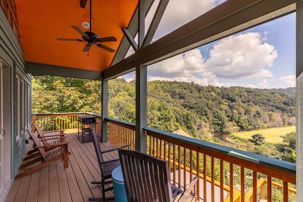 A covered outdoor seating area with comfortable furniture overlooks a scenic view. The ceiling fan above and the open sides create a breezy, inviting space ideal for gathering with friends or simply relaxing and enjoying the panoramic surroundings.